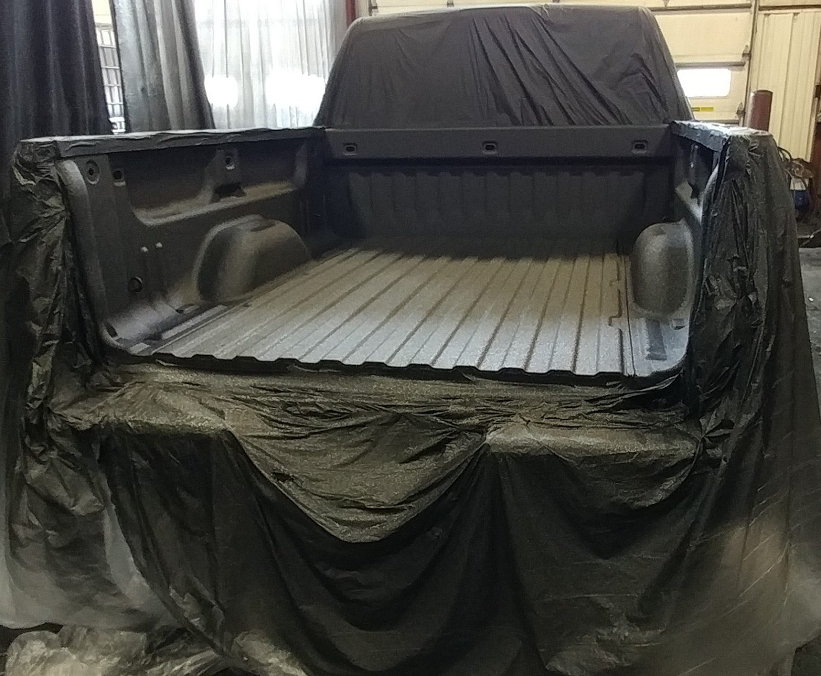 Applicator spraying plural-component polyurea anti rust coating on steel